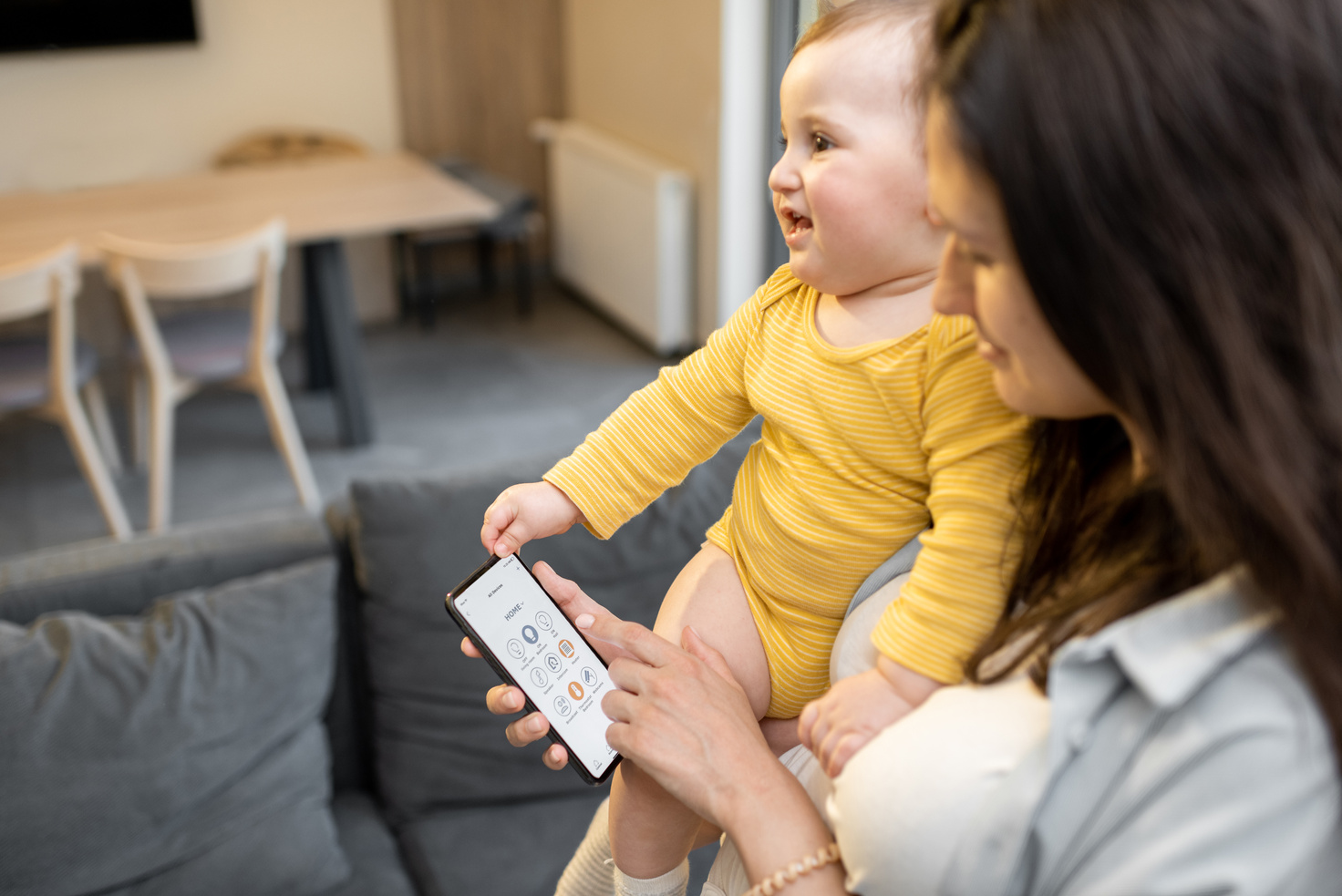 Woman Using a Smartphone While Carrying Her Baby